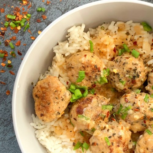 Curry turkey meatballs over rice in a grey bowl.