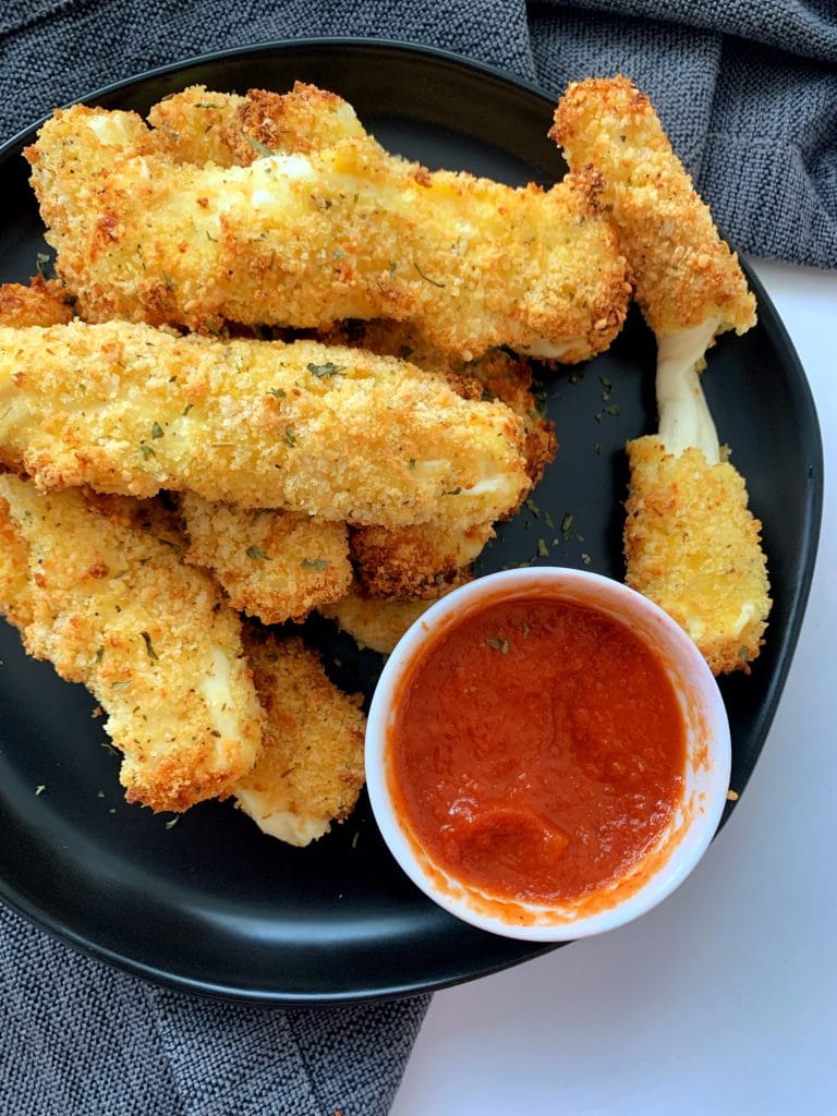 plate of air fried mozzarella sticks with marinara sauce on the side