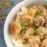 Curry turkey meatballs over rice in a grey bowl.