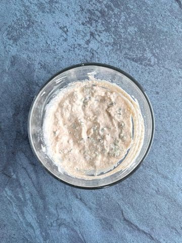 A glass bowl containing a white Mexican crema mixture with spices.
