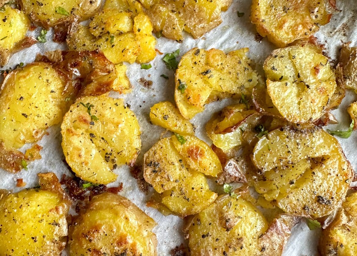 A tray of Crispy Garlic Smashed Potatoes on parchment paper.