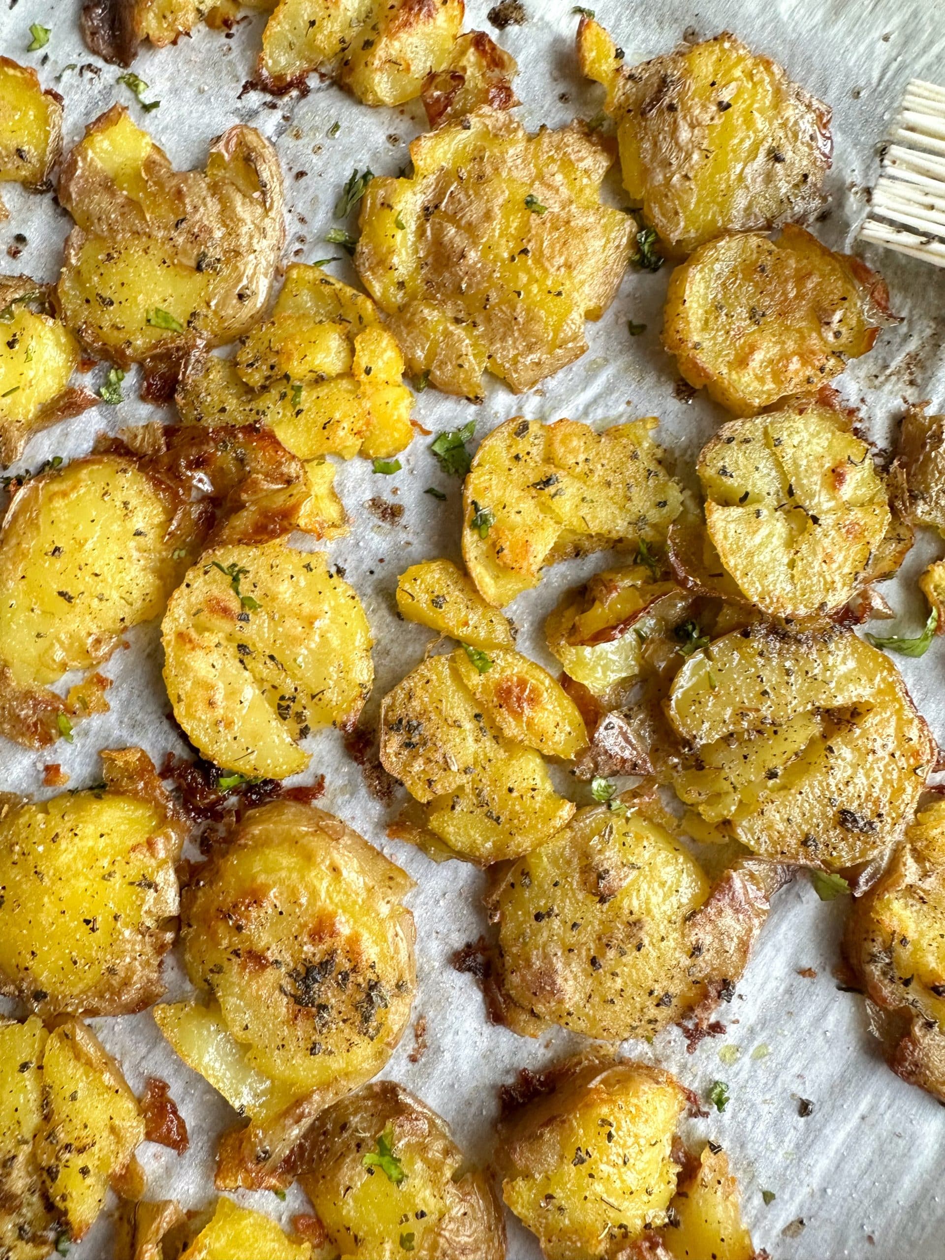 A tray of Crispy Garlic Smashed Potatoes on parchment paper.