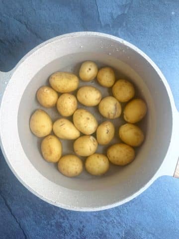 A large pot filled with water and petite gold potatoes.