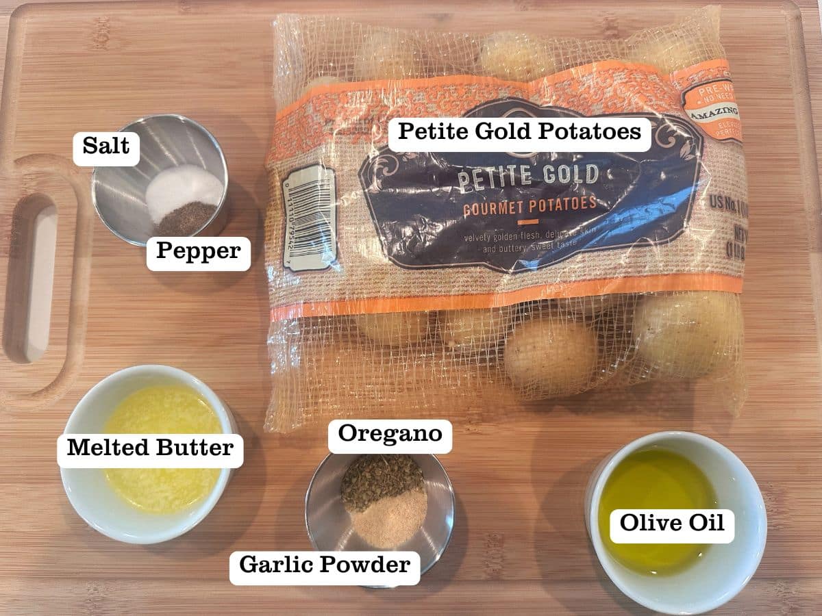 A wooden board containing a bag of petite gold potatoes and sauce cups of melted butter, olive oil, and seasonings.