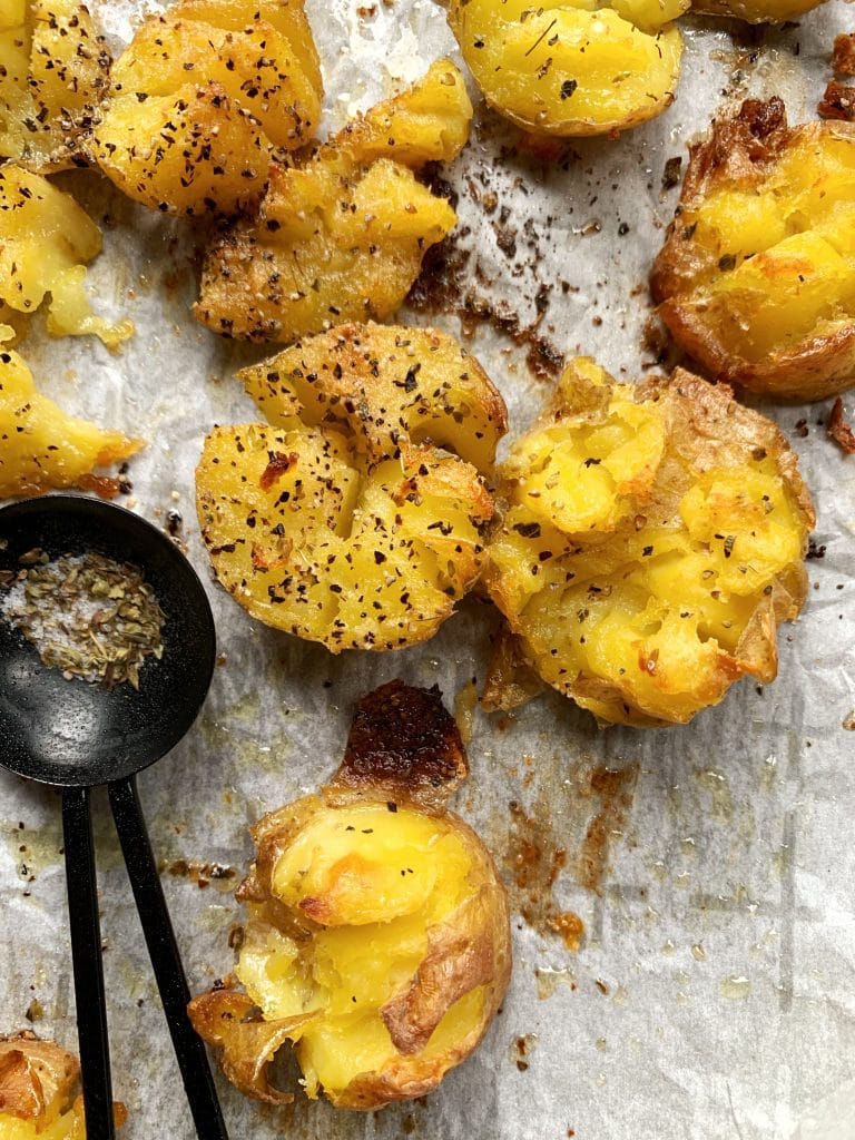 A pan of crispy smashed potatoes on a sheet of crumbled parchment paper.