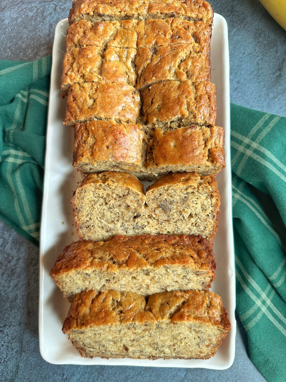 A loaf of sliced banana bread on a white serving platter.