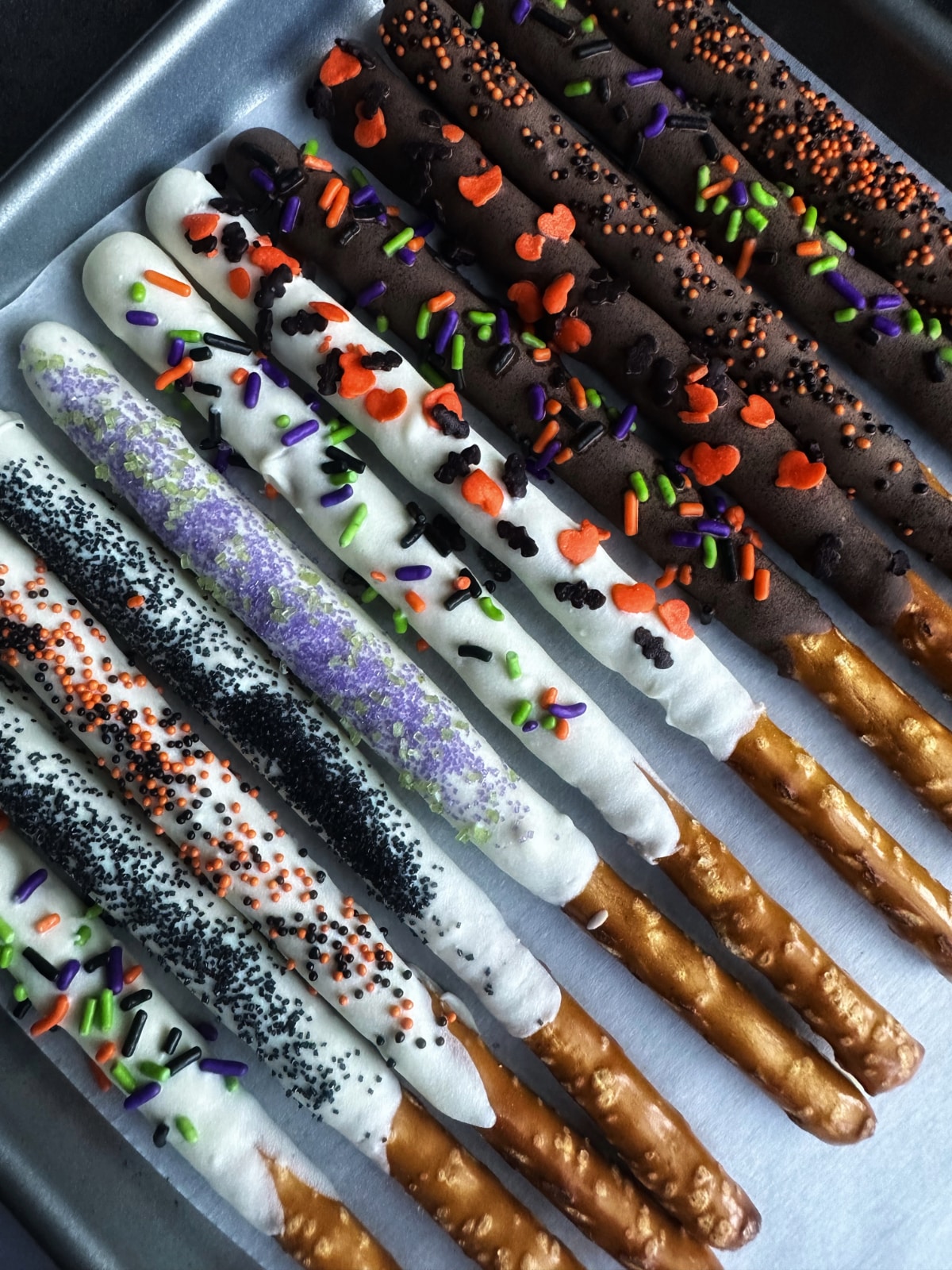 A tray of chocolate covered pretzels decorated in Halloween sprinkles.