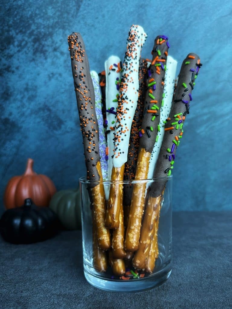 A cup of chocolate-covered pretzel rods decorated as "magic wands" for Halloween.