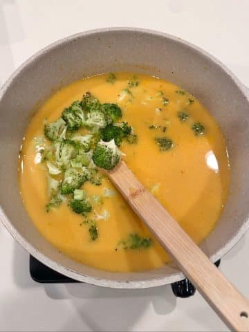 A pot of broccoli cheddar soup with roasted broccoli inside.