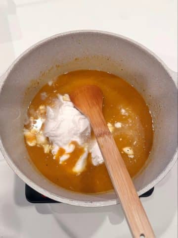 An orange colored soup with coconut cream poured in.