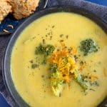 A bowl of broccoli cheddar soup with cheddar bay biscuits on the side