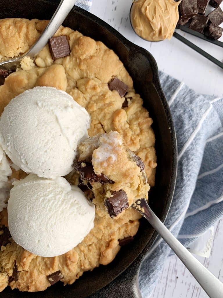 peanut butter chocolate chip cookie skillet with vanilla ice cream and spoons stuck inside