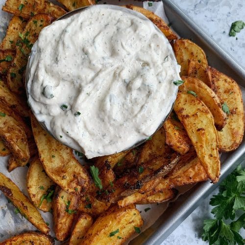 A tray of air fried potato wedges with a bowl of homemade ranch dip in the center.