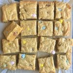 A block of Cadbury Mini Egg Blondies, cut into squares, on parchment paper.