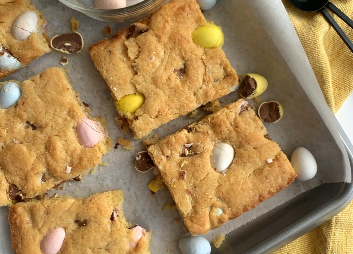 A tray of Mini Cadbury Egg Blondies with an extra bowl of cadbury eggs on the side.