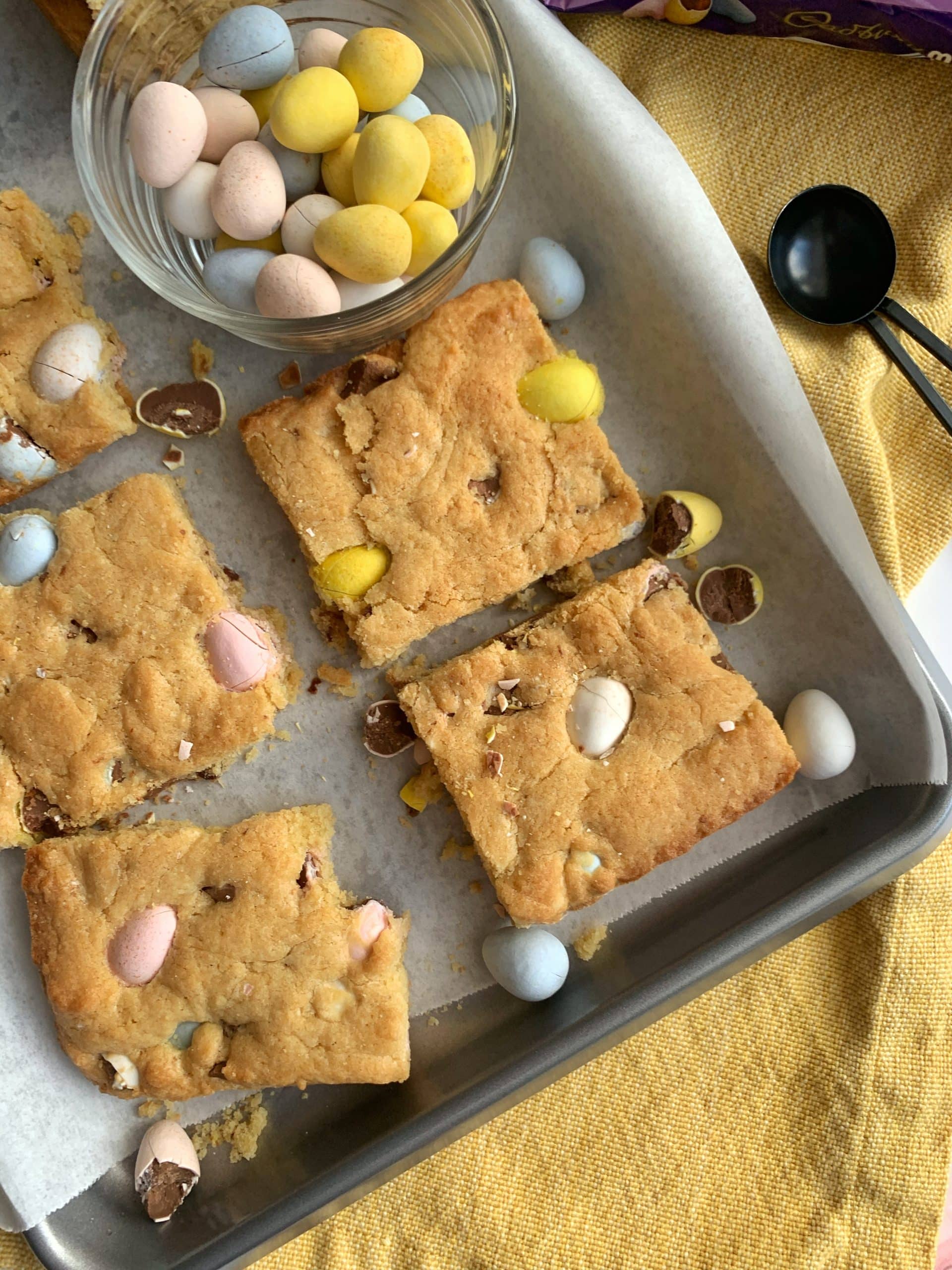 A tray of Mini Cadbury Egg Blondies with an extra bowl of cadbury eggs on the side.