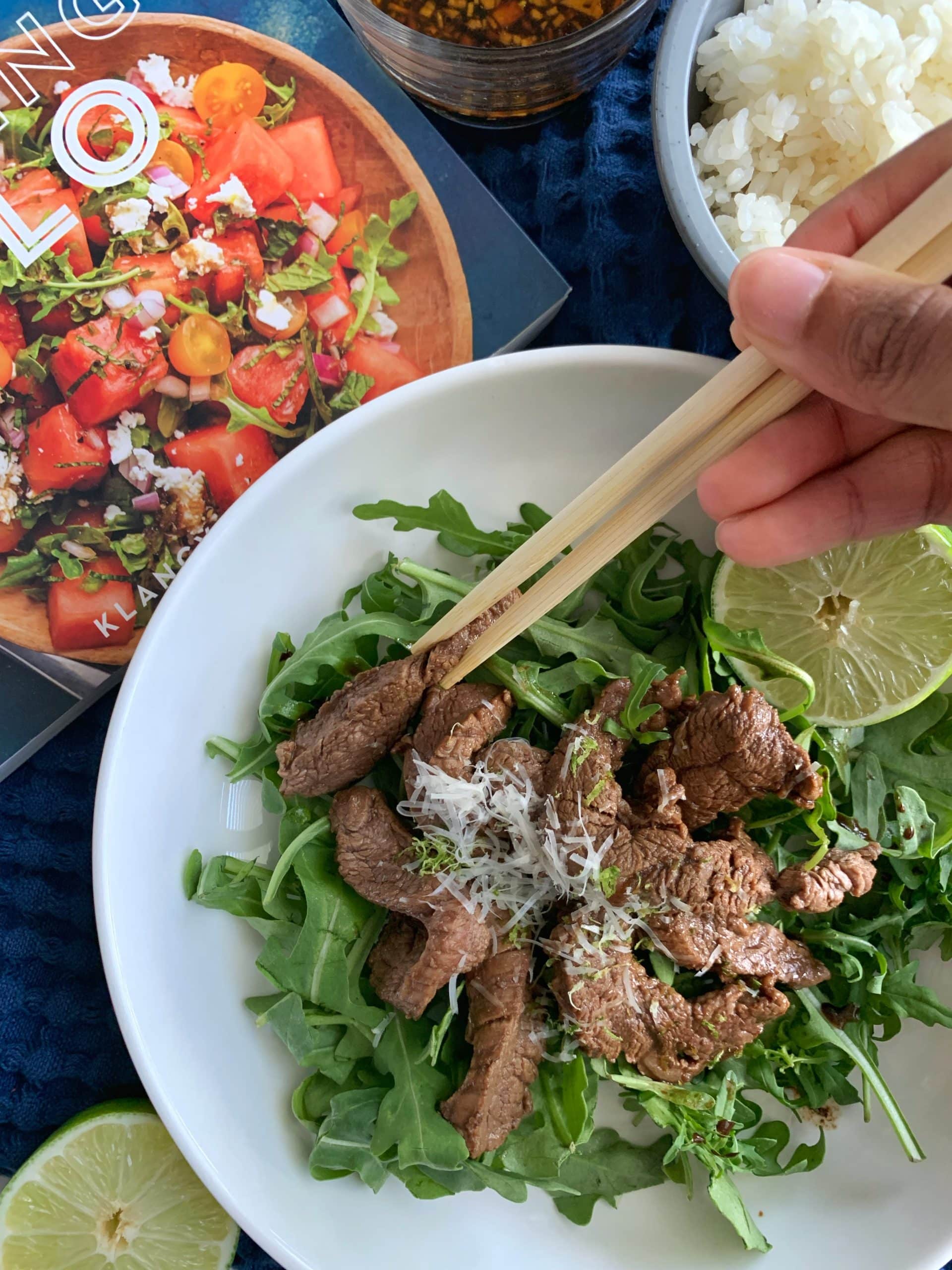 Soy-Lime Beef Stir Fry served over Arugula with Cooking Solo cookbook in the background.