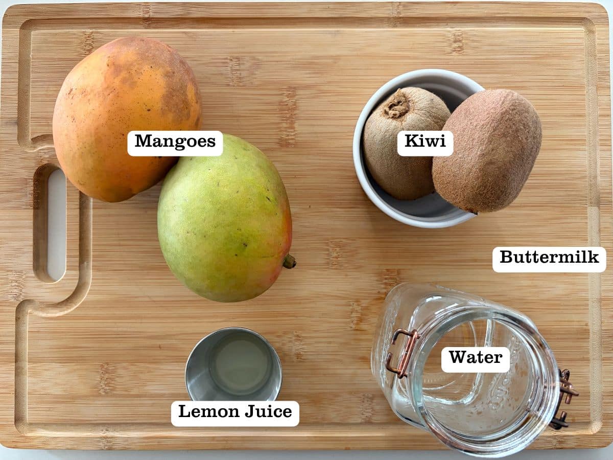 A wooden board filled with ingredients for mango-kiwi popsicles.