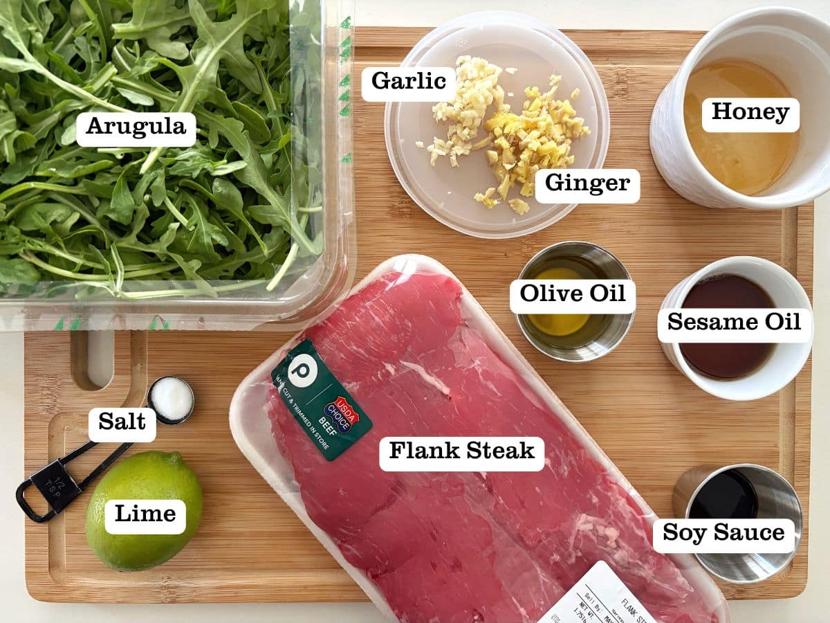 A wooden board with containers of ingredients for beef stir fry.