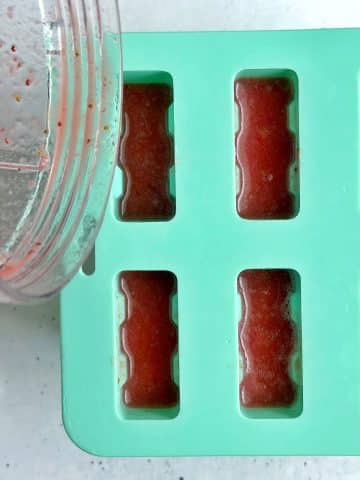 A silicone popsicle mold filled with strawberry juice.