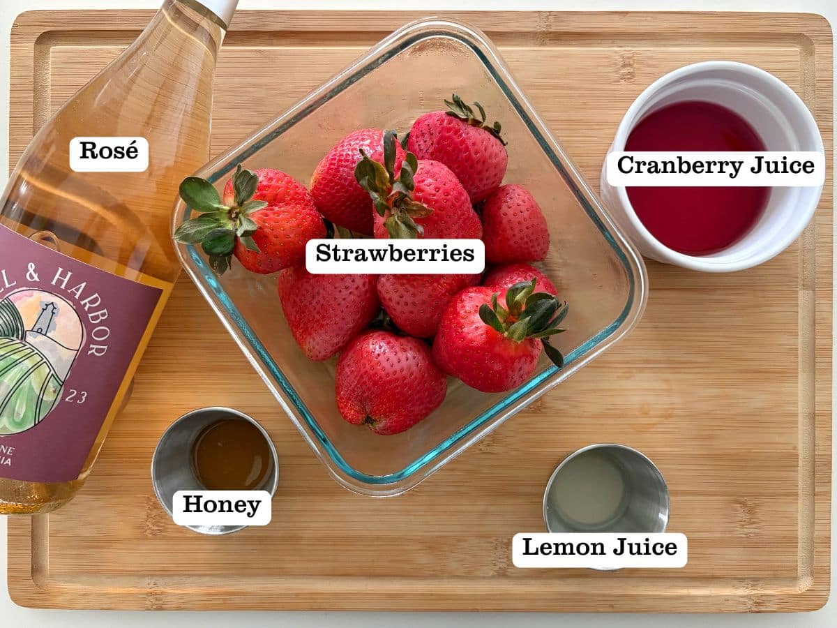 A wooden board with containers of ingredients for a strawberry frose popsicle.