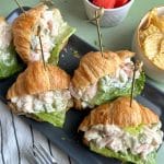 A tray of mini croissant sandwiches filled with shrimp salad.