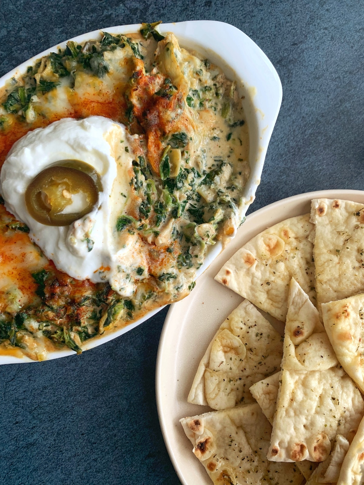 Hot Crab Spinach & Artichoke Dip in a white bowl with pita chips on the side.