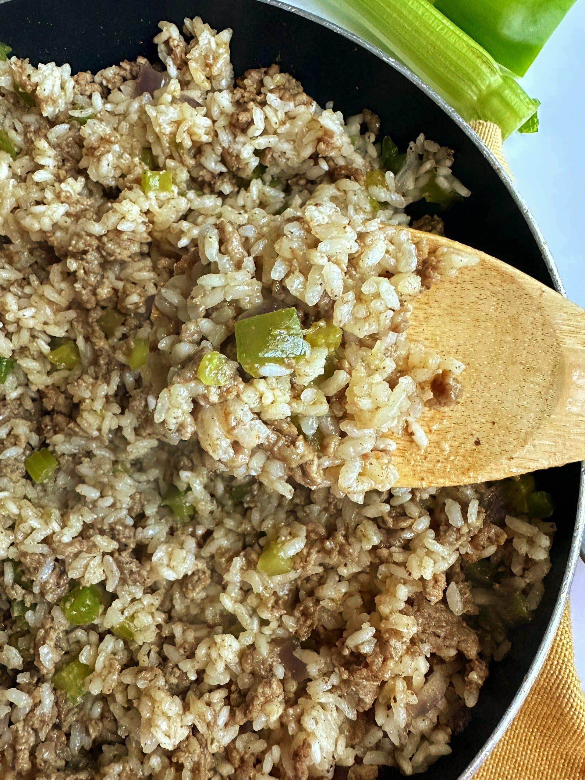 A pan full of homemade dirty rice with a serving spoon sticking out of it.