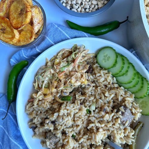 A bowl of Guyanese Cook Up Rice with black eyed peas, beef, plantains, cucumber, and slaw.