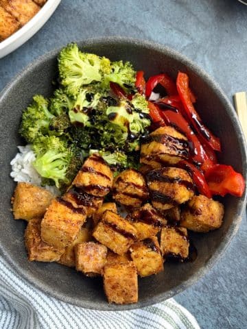A bowl filled with air fried tofu, rice, and veggies.