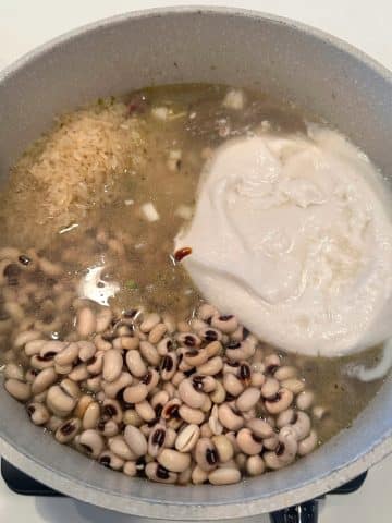 A pot of cook up rice with black eyed peas, broth, and coconut milk inside.