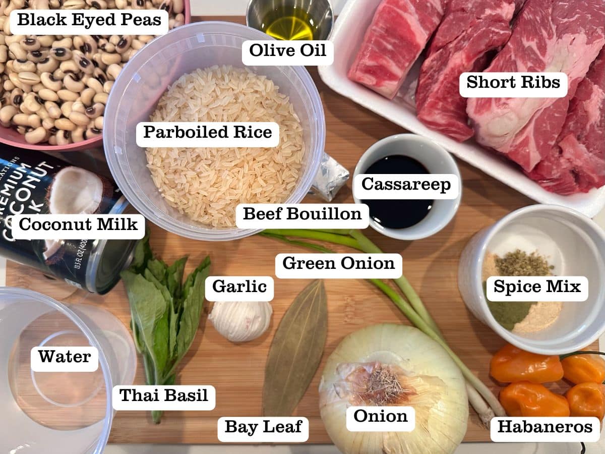 A wooden board filled with ingredients for guyanese cook up rice, including short ribs, black eyed peas, and coconut milk.