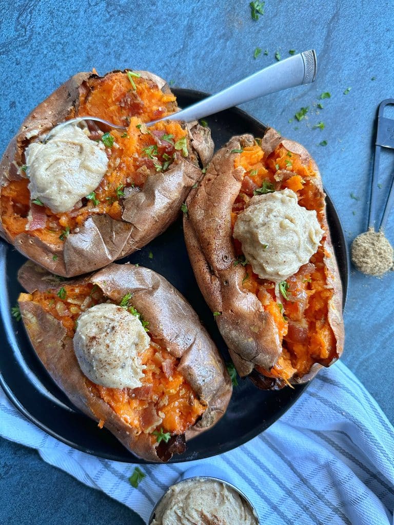 A plate of three baked sweet potatoes with plops of chai-spiced butter on top.