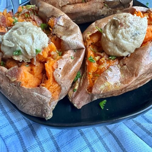A closeup of baked sweet potatoes with plops of chai-spiced butter on top.