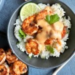 A bowl of Grilled Bang Bang Shrimp over cilantro-lime rice with a lime on the side.