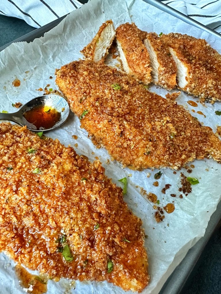 A tray of baked panko-covered hot honey chicken breasts.