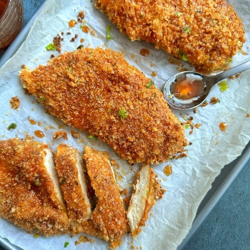 A tray of baked panko-covered hot honey chicken breasts.