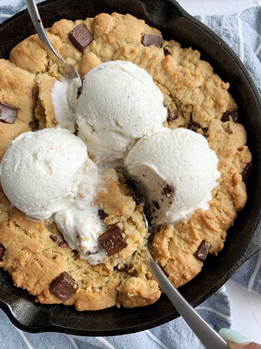A Peanut Butter Chocolate Chip Cookie Skillet with ice cream dollops on top.