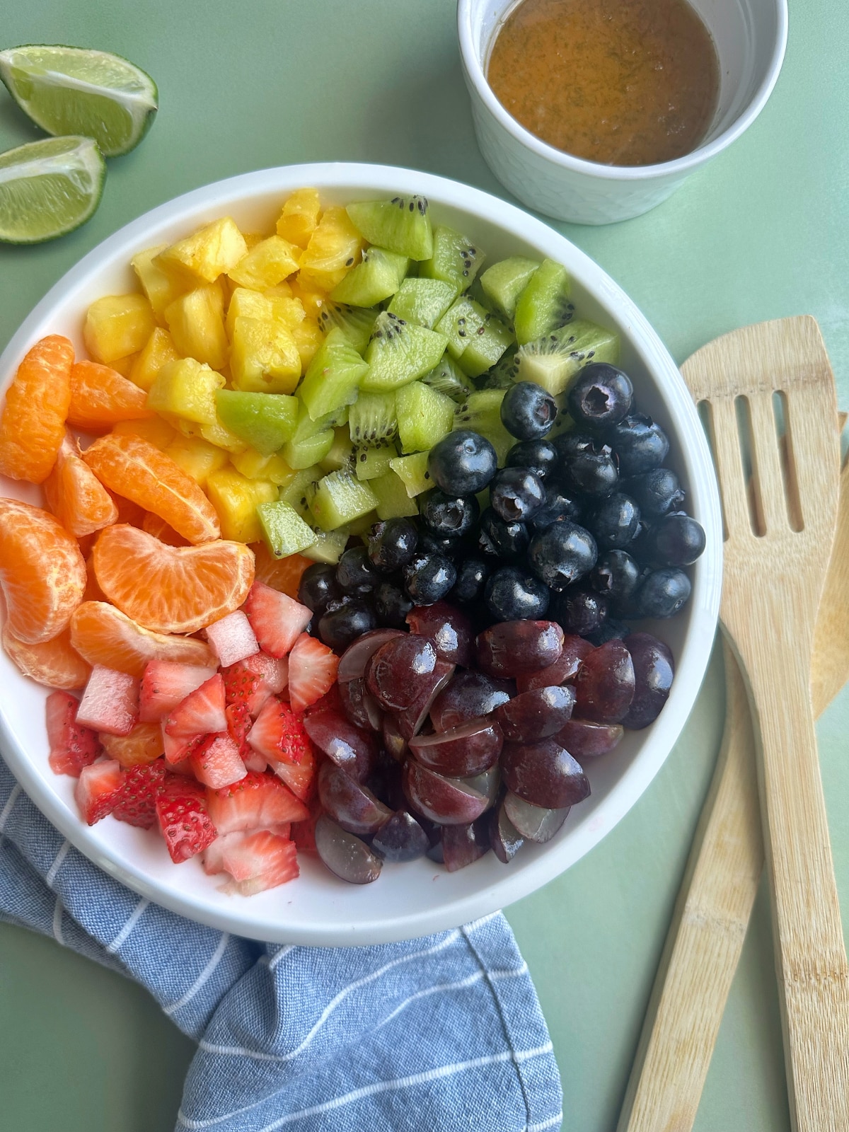 A white bowl filled with fruit salad with an agave-lime syrup on the side.