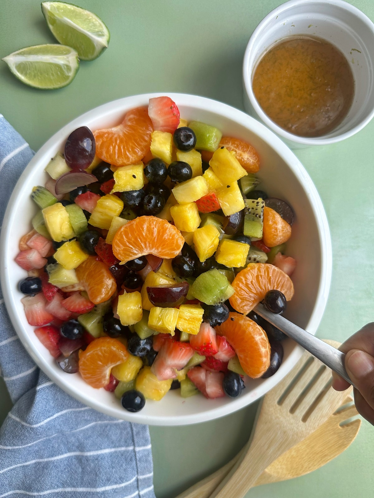 A spoon stirring up a bowl of fruit salad.