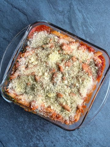 A square baking dish filled with a pasta dish and panko crust, before baking.