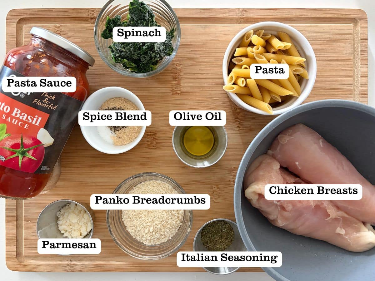 A wooden board with containers of ingredients for a chicken parmesan pasta bake.