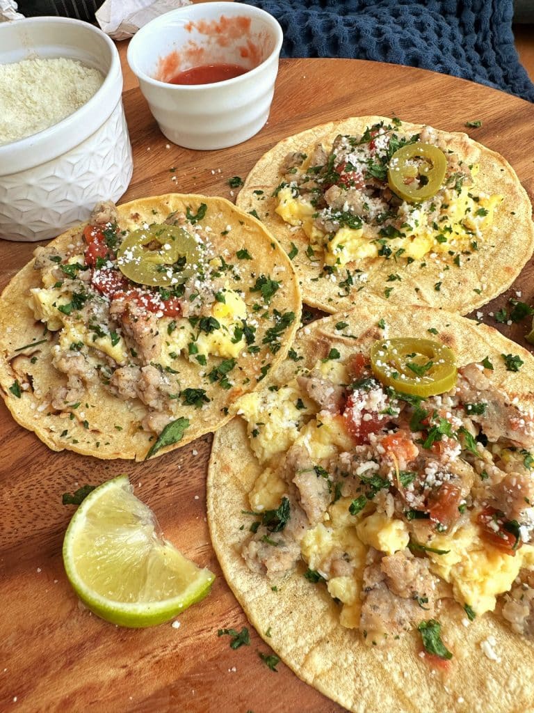 A closeup shot of a platter of 3 homemade breakfast tacos made with chicken sausage and scrambled egg.