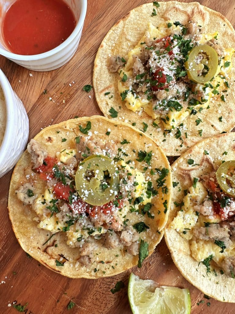 A closeup shot of a platter of 3 homemade breakfast tacos made with chicken sausage and scrambled egg.