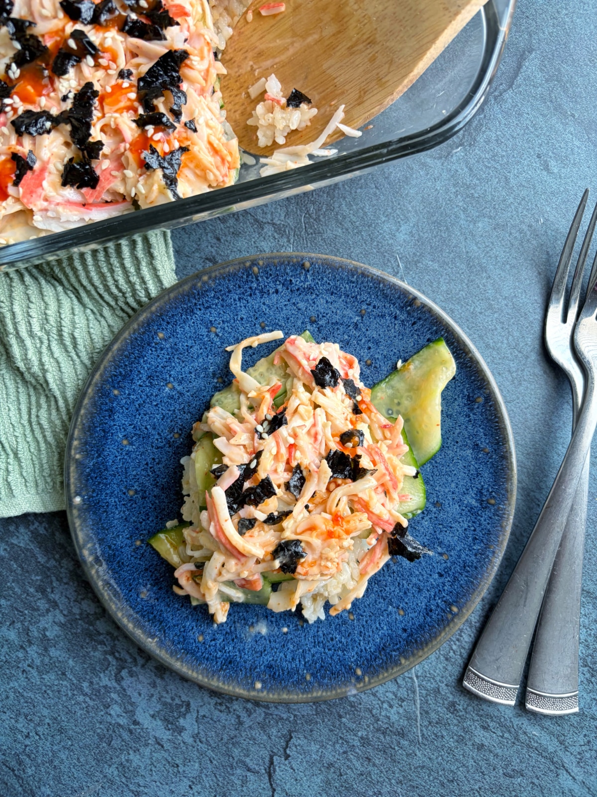 A plate of crab sushi bake with the rest of the pan on the side.