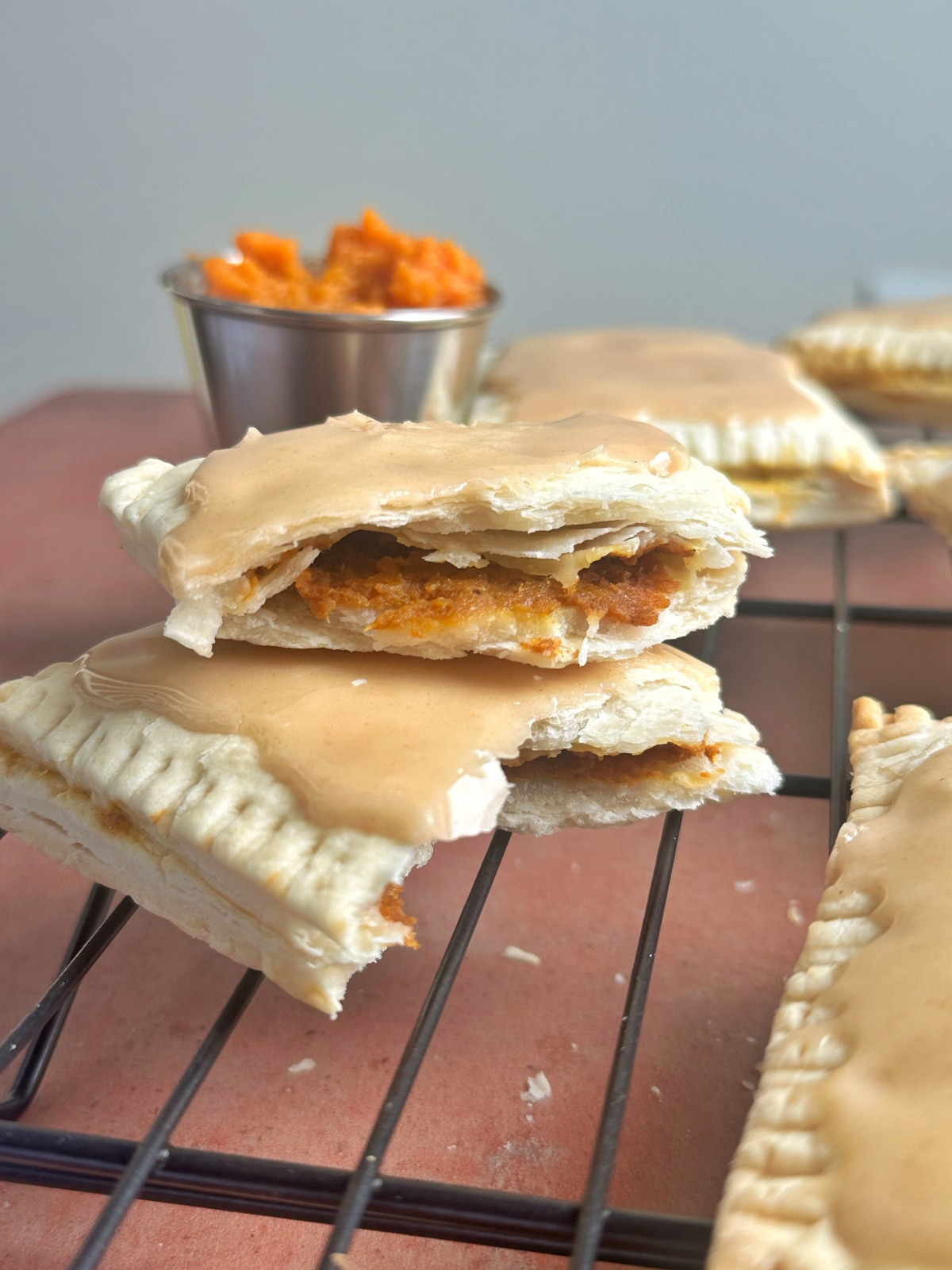 A pumpkin pie pop tart broken in half and stacked on top of each other to display the inside texture and brown-orange color.