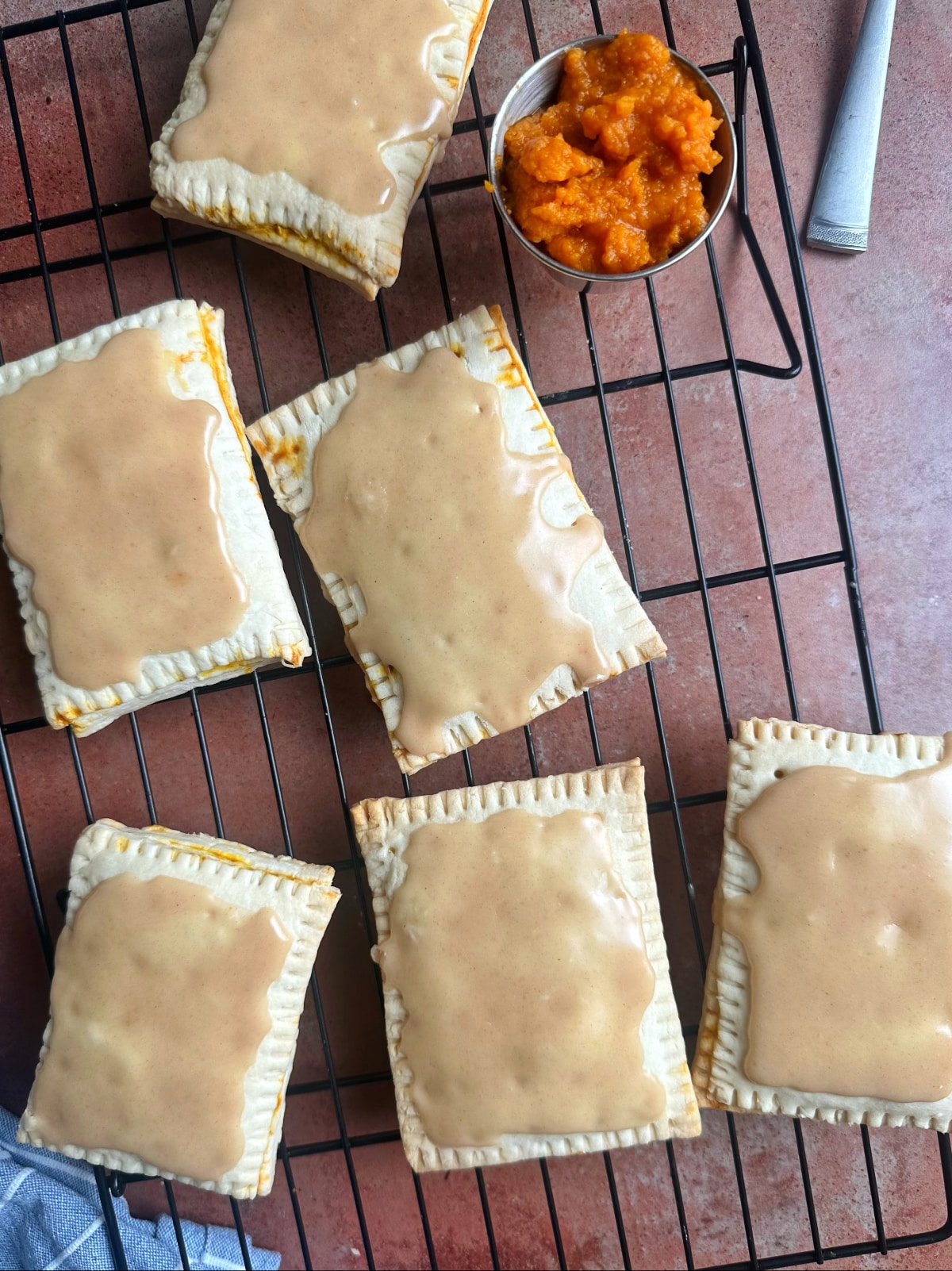 Pumpkin-flavored homemade pop tarts with a brown icing on top of a wire rack.