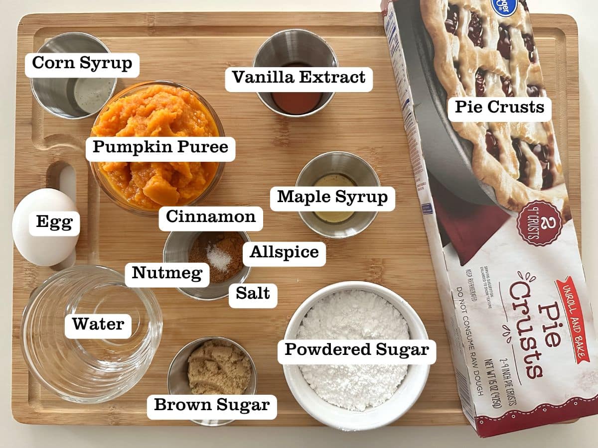 A wooden board containing bowls of ingredients for homemade pumpkin pie pastries.
