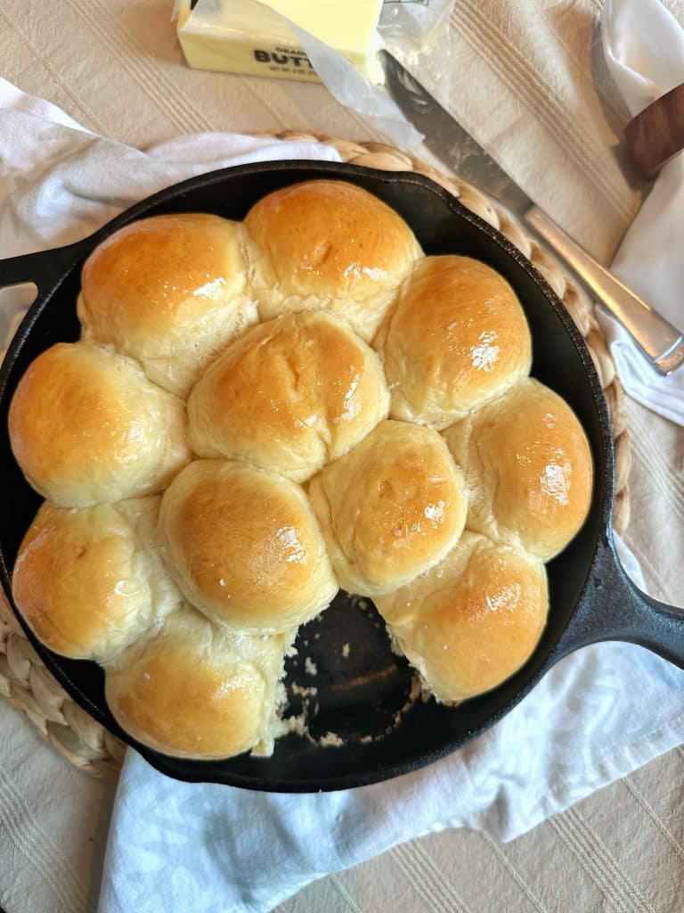 A cast iron skillet with golden brown, homemade yeast dinner rolls.