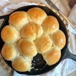 A cast iron skillet with golden brown, homemade yeast dinner rolls.